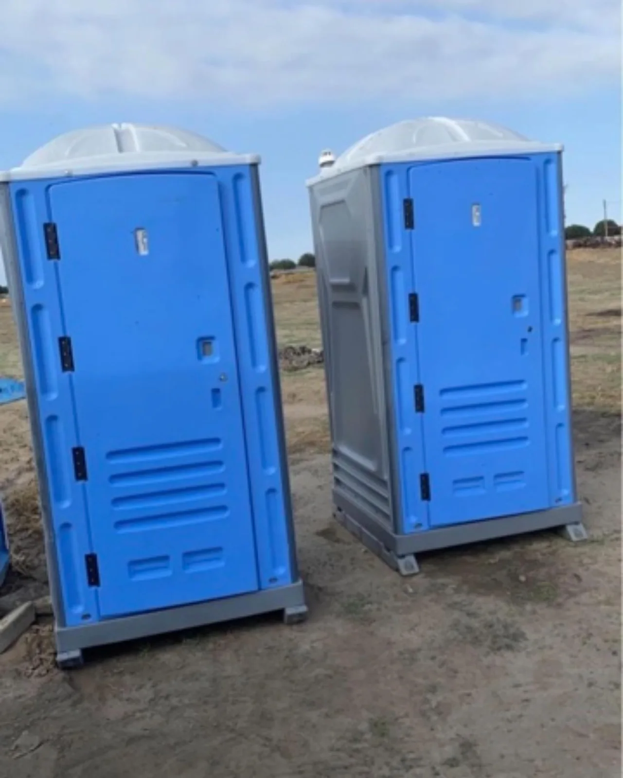 Two blue portable toilets with light gray roofs outdoors
